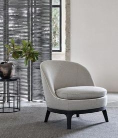 a living room with a chair, table and vase on the floor next to it