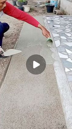 a woman kneeling down to paint a sidewalk