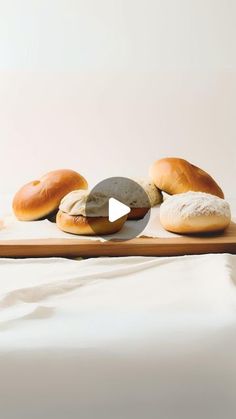 breads and rolls on a wooden tray with white sheets in the backround