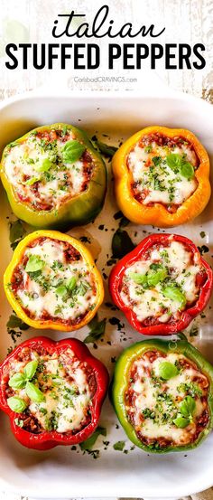 several stuffed peppers in a white casserole dish with cheese and herbs on top