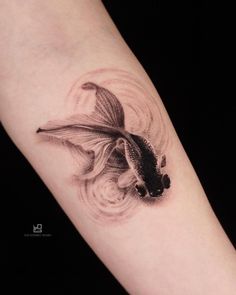 a black and white photo of a goldfish tattoo on the left arm with swirls around it