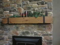 a stone fireplace with candles and greenery on the mantle