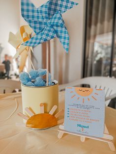 a table topped with a potted plant next to a sign and stuffed animals on top of it