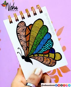 a hand holding up a colorful butterfly sticker on top of a notepad with writing underneath it