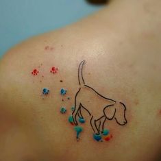 a small dog tattoo on the back of a woman's left shoulder, with sprinkles all over it