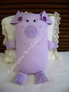 a purple pig stuffed animal sitting on top of a white bed covered in ruffles