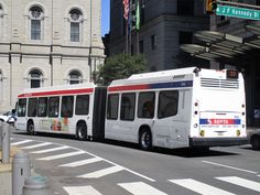 two buses are parked on the side of the street in front of a large building