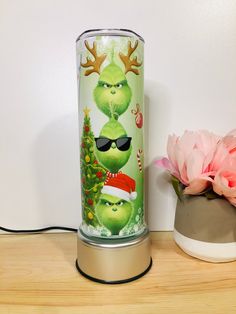 the grinch characters are wearing sunglasses and santa hats on this glass vase next to a pink flower