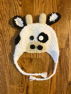 a crocheted animal hat with ears and eyes on top of a wooden floor