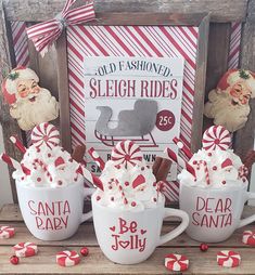 three mugs with hot chocolate and marshmallows in front of a sign