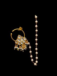 a pair of pearls and gold ear rings on a black background with a beaded chain