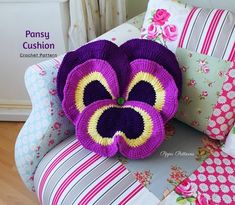 a crocheted flower sitting on top of a couch next to pillows and pillow cases