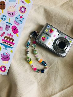 a camera and some stickers are laying on a bed next to a bookmark