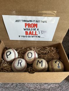 four baseballs in a cardboard box with the word prom written on them