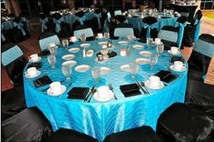 a blue table cloth with white plates and silverware is set up for a formal function