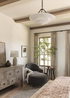 a bedroom with a bed, dresser and chair next to a window in the room