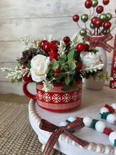 a red and white flower pot sitting on top of a table next to christmas decorations