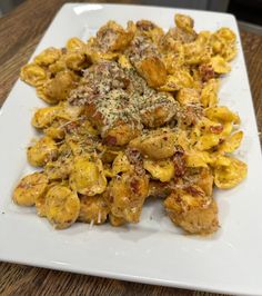 a white plate topped with pasta covered in sauce and cheese on top of a wooden table