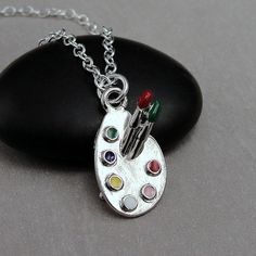 "This Artist Palette Charm necklace comes on a silver-plated chain that is available in different lengths. Please choose your desired length from the drop-down menu when placing the item in your shopping cart.  { CHARM DETAILS } ★ Material: Pewter  ★ Finish Color: Silver  ★ Measurements: 1/2\" x 7/8\" ★ Dimensions: 3-Dimensional ★ Made in the USA { SIMILAR ITEMS }  More art themed items available from my shop: https://www.etsy.com/shop/treasuredcharms/search?search_query=art { GIFT OPTIONS} Gift Artistic Nickel-free Silver Necklaces, Artist Jewelry, Artist Palette, Artist Gifts, Paint Palette, Necklace Silver, Art Gift, Shopping Cart, Silver Necklaces