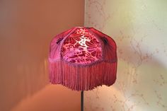 a red lamp with fringes on it next to a wall