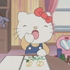 hello kitty sitting at a table with scissors