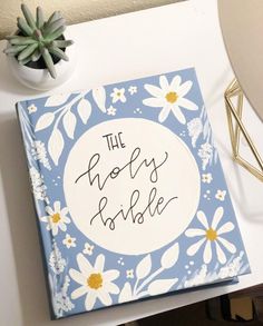 a blue and white book sitting on top of a table next to a potted plant