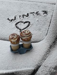 two cupcakes sitting on top of a car covered in snow