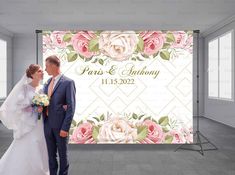 a newly married couple standing in front of a floral backdrop