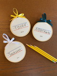 three personalized embroidered ornaments with pencils on a table