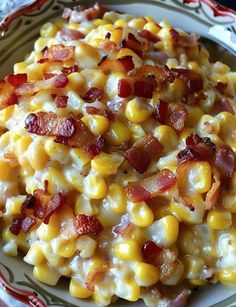 a white plate topped with corn and bacon covered in cheese on top of a table