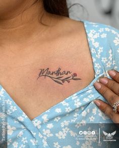 a woman's chest with the word manhattan tattooed on her left shoulder and an arrow in the center