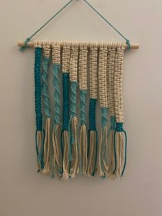 a wall hanging made out of macrame and rope with blue tassels