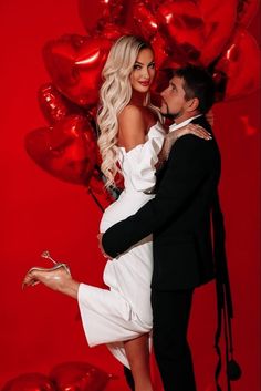 a man and woman posing in front of red balloons