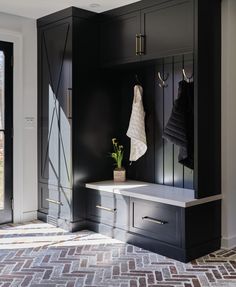 an entryway with black cabinets and white countertop, potted plant in the corner