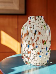 a vase sitting on top of a blue table next to a wooden paneled wall