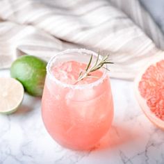 a pink drink with a sprig of rosemary garnish