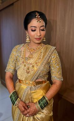 a woman in a gold and green sari is posing for the camera with her hands on her hips