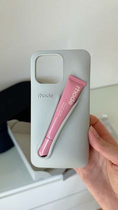 a pink toothbrush sitting on top of a white phone case next to a box