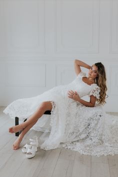 a woman is sitting on the floor in a white dress and shoes with her legs crossed