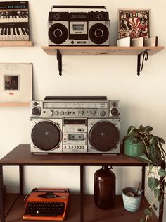 an old fashioned radio sitting on top of a wooden table next to a keyboard and potted plant