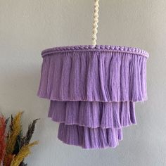 a purple chandelier hanging from a white wall next to dried flowers and plants