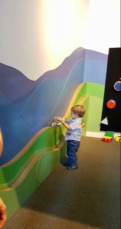 a little boy playing with toys in a play area at the children's museum