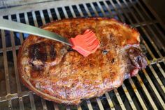 a steak being cooked on the grill with a spatula and tongs in it