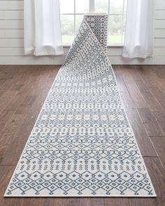 a blue and white runner rug on a wooden floor in front of a large window