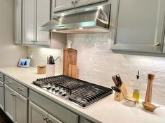 a stove top oven sitting inside of a kitchen next to wooden cutting boards and utensils