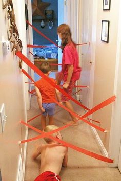 two children are playing with red tape in the hallway while another child is on the floor