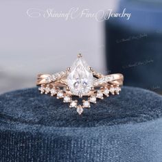 an engagement ring with a pear shaped diamond surrounded by smaller round diamonds on top of it