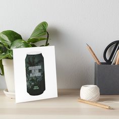 a green beer can sitting on top of a wooden table next to a potted plant