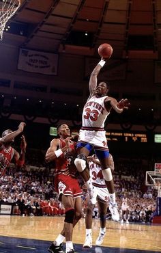 a basketball player jumping up to dunk the ball in front of two other players