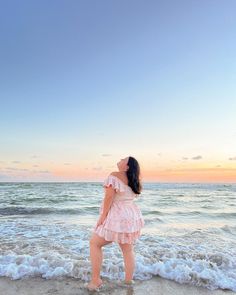 a woman standing on top of a sandy beach next to the ocean